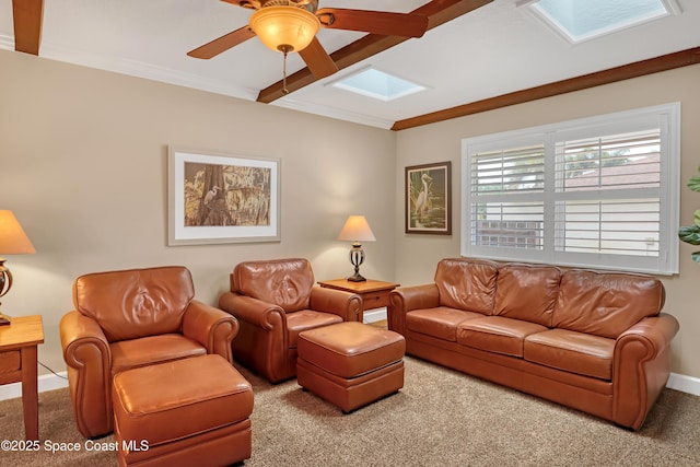 living room featuring a ceiling fan, carpet floors, ornamental molding, and a skylight