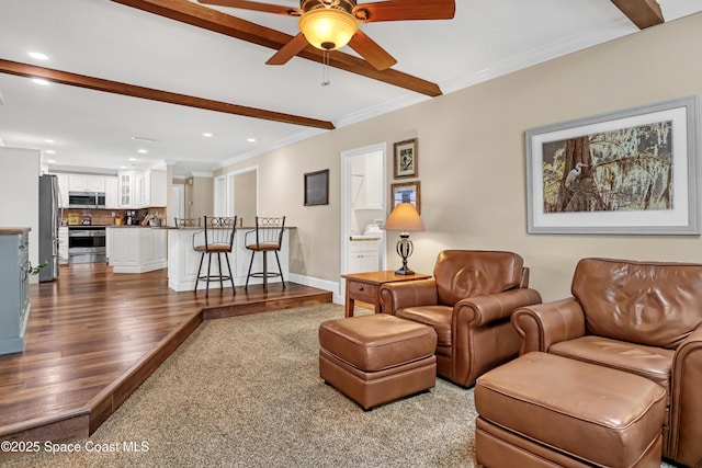 living area featuring a ceiling fan, recessed lighting, ornamental molding, dark wood finished floors, and beamed ceiling