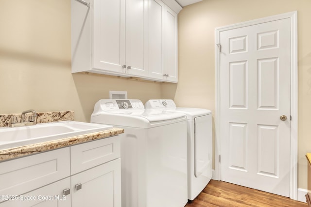 washroom with a sink, cabinet space, light wood-type flooring, and independent washer and dryer