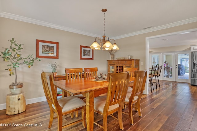 dining room with wood finished floors, baseboards, ornamental molding, and a notable chandelier