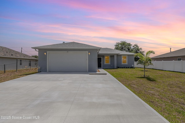 view of front of home with concrete driveway, fence, a front lawn, and an attached garage