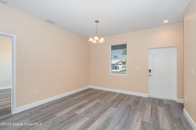 spare room featuring wood finished floors, visible vents, recessed lighting, a chandelier, and baseboards