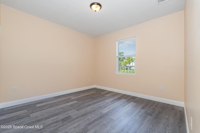 spare room featuring baseboards and dark wood-style floors