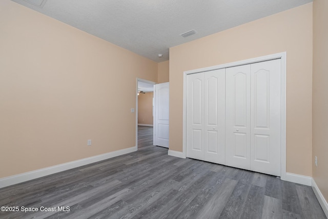 unfurnished bedroom featuring a closet, dark wood-type flooring, baseboards, and visible vents