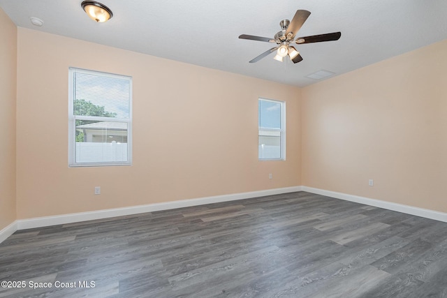 empty room featuring baseboards, dark wood-style floors, a ceiling fan, and visible vents