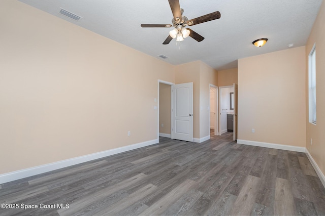 empty room with baseboards, a ceiling fan, visible vents, and wood finished floors