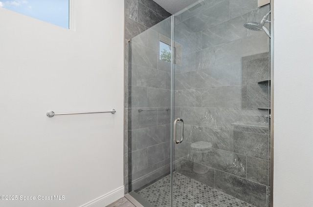full bath featuring a shower stall and baseboards