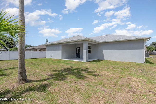 rear view of house with a lawn, fence, a patio, stucco siding, and an attached carport