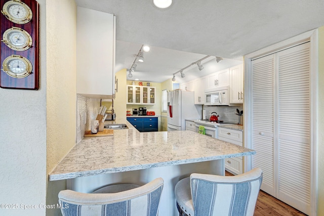 5011 Dixie Hwy NE Unit A312, Palm Bay, FL 32905 - kitchen with white appliances, a sink, a kitchen breakfast bar, a peninsula, and white cabinetry