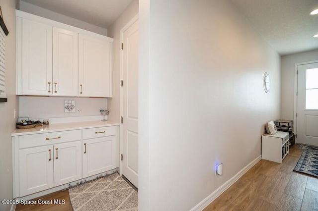 2979 Pangea Cir, Melbourne, FL 32940 - kitchen with light wood-style flooring, white cabinetry, light countertops, baseboards, and recessed lighting