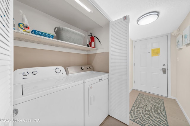 laundry area featuring washing machine and clothes dryer, light tile patterned floors, baseboards, and laundry area