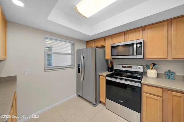 kitchen with light tile patterned floors, light countertops, stainless steel appliances, and baseboards