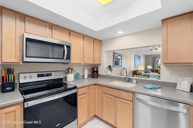kitchen with a sink, stainless steel appliances, and light brown cabinetry