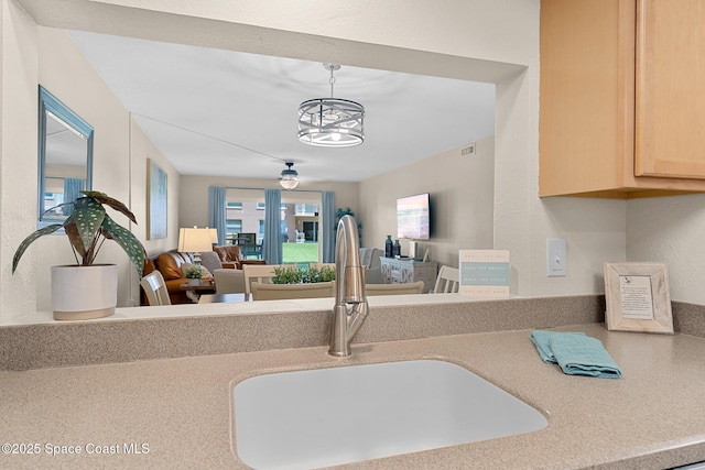 kitchen featuring a sink, an inviting chandelier, light brown cabinetry, open floor plan, and light countertops