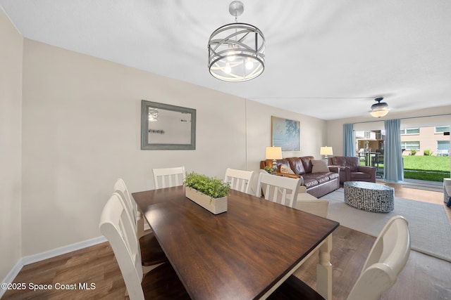 dining room featuring an inviting chandelier, wood finished floors, and baseboards