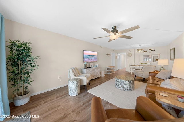 living area featuring light wood finished floors, baseboards, and a ceiling fan