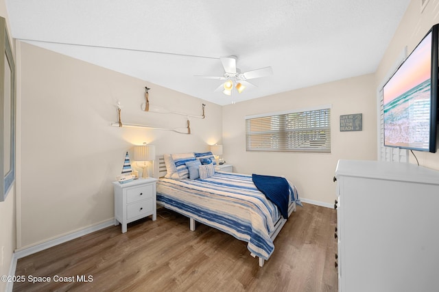 bedroom with a ceiling fan, wood finished floors, and baseboards