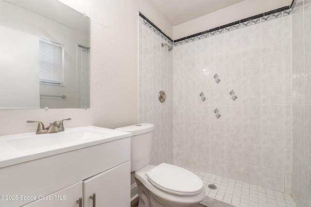 full bath with toilet, vanity, and tiled shower