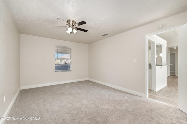 spare room with ceiling fan, light colored carpet, a textured ceiling, and baseboards