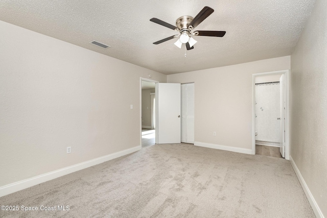 unfurnished bedroom featuring carpet flooring, a textured ceiling, connected bathroom, baseboards, and ceiling fan