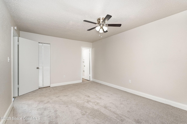 unfurnished bedroom featuring carpet, baseboards, a textured ceiling, a closet, and ceiling fan