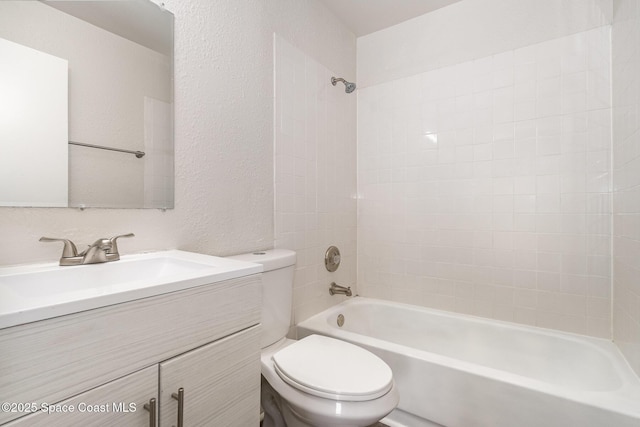full bath with toilet,  shower combination, vanity, and a textured wall