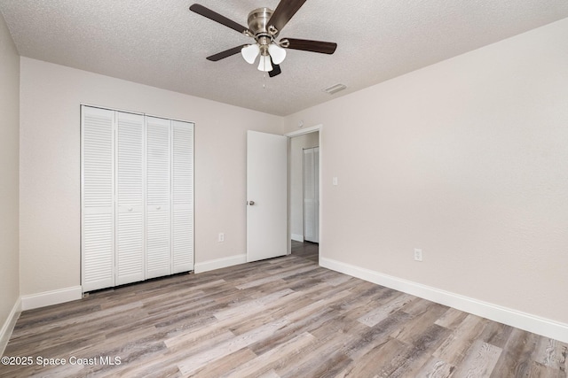 unfurnished bedroom featuring wood finished floors, baseboards, a textured ceiling, a closet, and ceiling fan