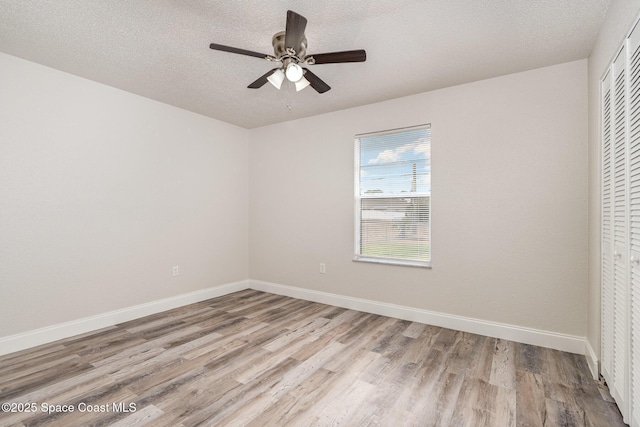 empty room with wood finished floors, ceiling fan, baseboards, and a textured ceiling