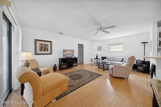 living area featuring a ceiling fan, light wood-type flooring, and visible vents