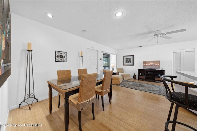 dining area with light wood finished floors, a textured ceiling, baseboards, and a ceiling fan