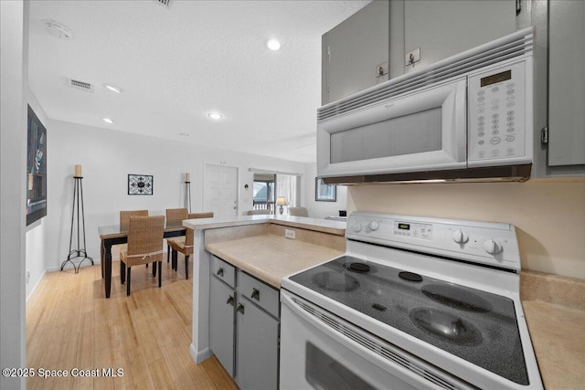 kitchen featuring white appliances, light wood-type flooring, visible vents, recessed lighting, and gray cabinetry