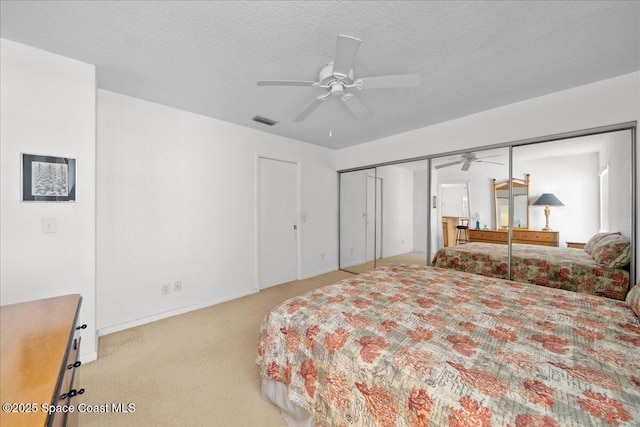 bedroom featuring a ceiling fan, a textured ceiling, visible vents, baseboards, and light carpet
