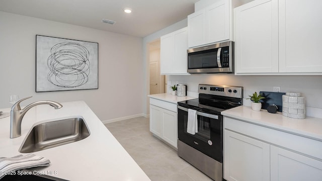 kitchen with a sink, stainless steel appliances, visible vents, white cabinetry, and light countertops