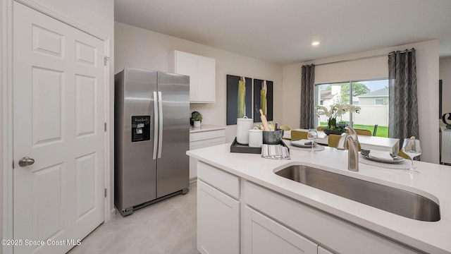 kitchen with a sink, white cabinetry, stainless steel fridge with ice dispenser, and light countertops