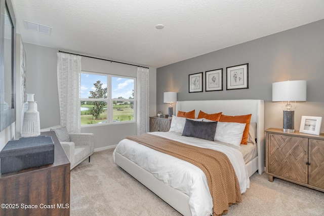 bedroom with baseboards, carpet flooring, visible vents, and a textured ceiling