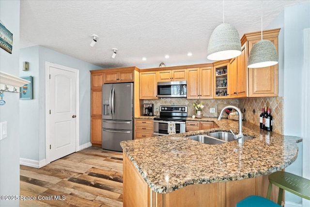 505 Tradewinds Dr, Indian Harbour Beach, FL 32937 - kitchen with a peninsula, a sink, stainless steel appliances, light stone countertops, and light wood-style floors