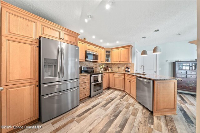 505 Tradewinds Dr, Indian Harbour Beach, FL 32937 - kitchen with a sink, a peninsula, appliances with stainless steel finishes, stone counters, and light wood-style floors