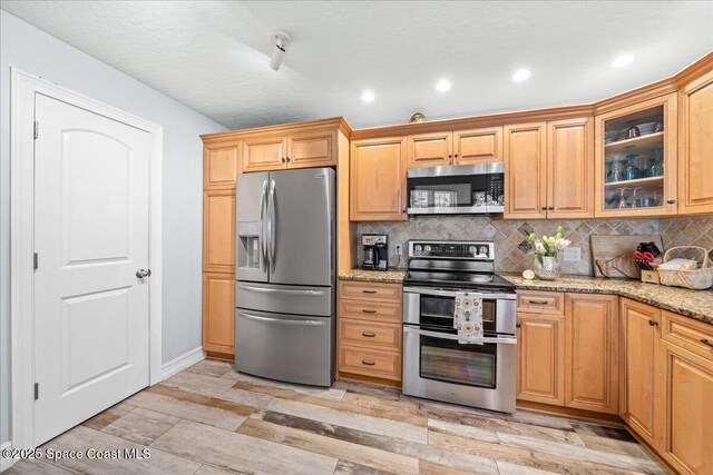 505 Tradewinds Dr, Indian Harbour Beach, FL 32937 - kitchen featuring glass insert cabinets, light stone countertops, backsplash, appliances with stainless steel finishes, and recessed lighting