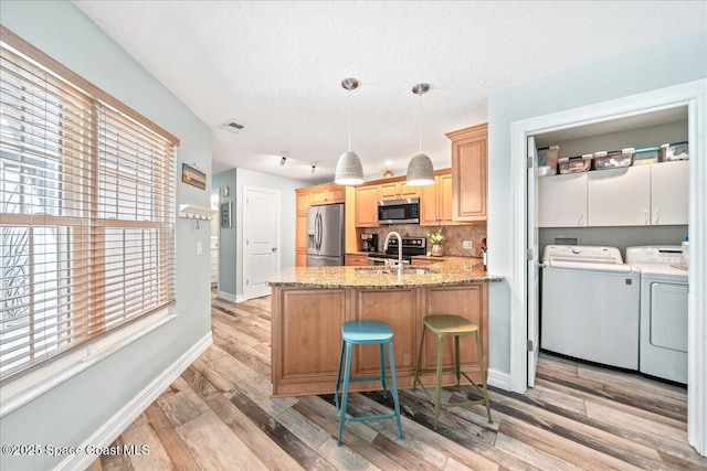 505 Tradewinds Dr, Indian Harbour Beach, FL 32937 - kitchen with a sink, a peninsula, stainless steel appliances, washer and dryer, and decorative backsplash