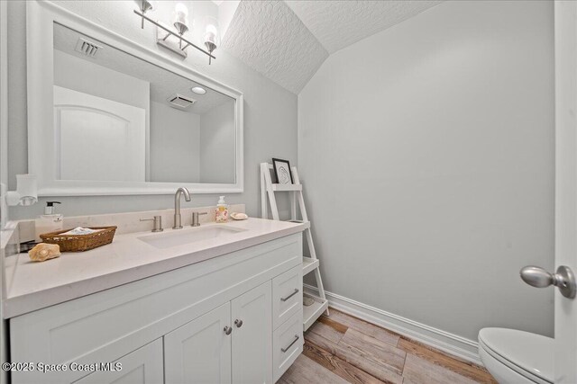 505 Tradewinds Dr, Indian Harbour Beach, FL 32937 - bathroom with a textured ceiling, baseboards, visible vents, vanity, and wood finished floors