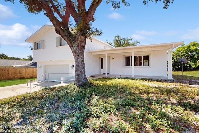 view of front of property featuring fence, an attached garage, concrete driveway, and stucco siding