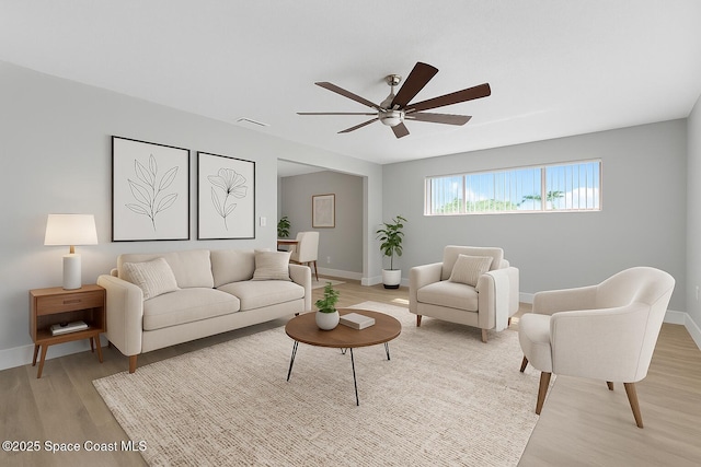 living room with a ceiling fan, light wood-style floors, and baseboards