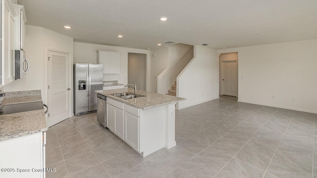kitchen with a sink, stainless steel appliances, a kitchen island with sink, recessed lighting, and light tile patterned floors