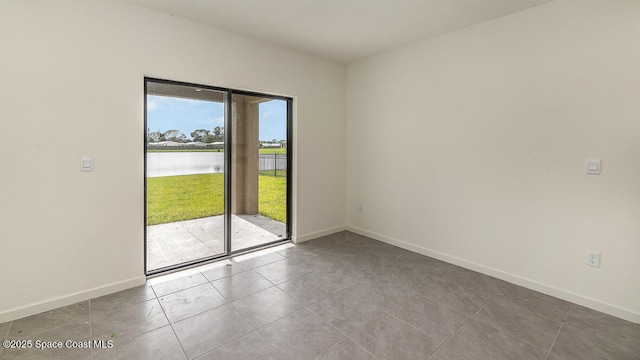 tiled spare room featuring a water view and baseboards
