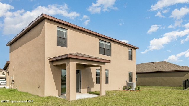 rear view of property featuring central air condition unit, stucco siding, a patio area, and a yard