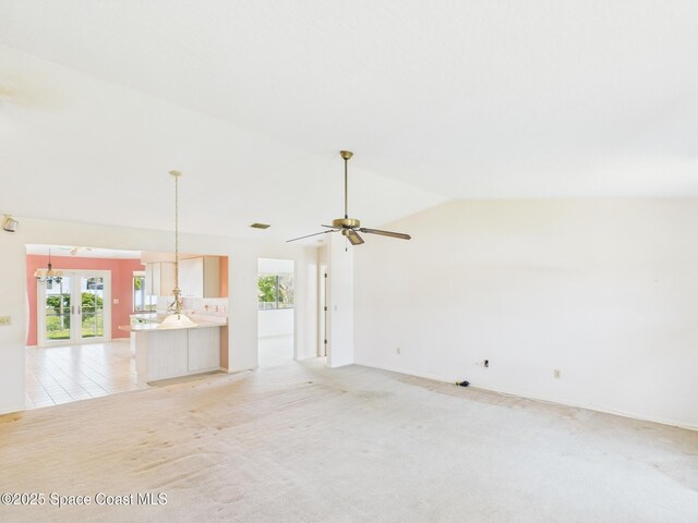 unfurnished living room featuring light carpet, ceiling fan, lofted ceiling, and baseboards