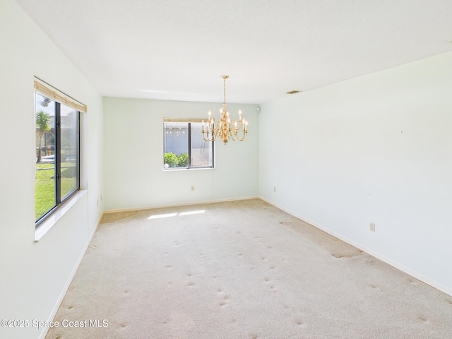 carpeted spare room featuring an inviting chandelier, visible vents, and baseboards