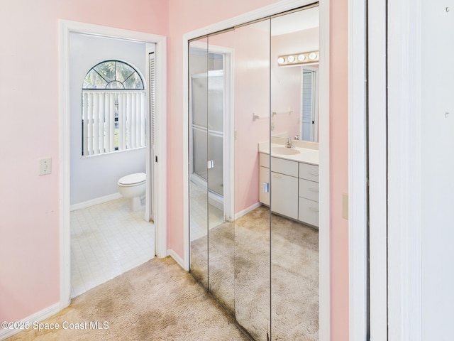 bathroom featuring vanity, toilet, baseboards, and tile patterned floors