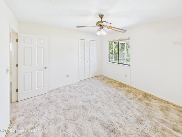 unfurnished bedroom featuring baseboards, carpet floors, a closet, and a ceiling fan
