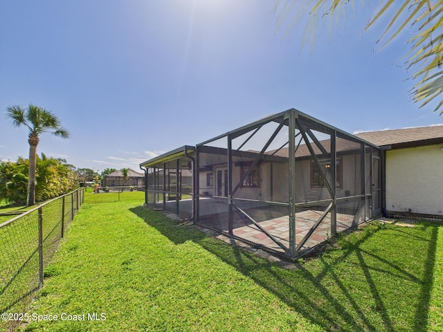 exterior space featuring a lawn, glass enclosure, a patio, and fence